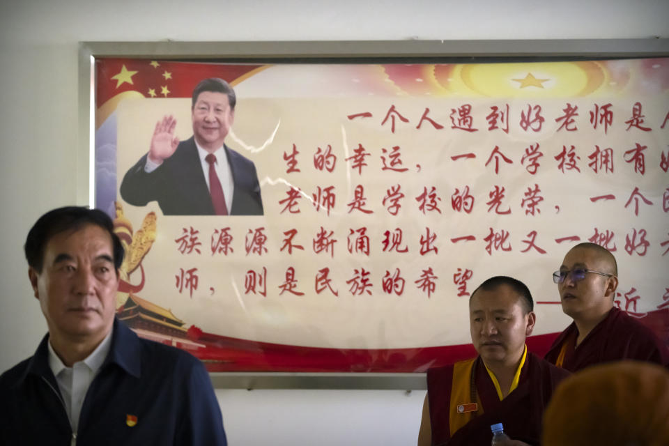 Monks and Chinese government officials stand near a billboard depicting Chinese President Xi Jinping at the Tibetan Buddhist College near Lhasa in western China's Tibet Autonomous Region, as seen during a rare government-led tour of the region for foreign journalists, Monday, May 31, 2021. Long defined by its Buddhist culture, Tibet is facing a push for assimilation and political orthodoxy under China's ruling Communist Party. (AP Photo/Mark Schiefelbein)