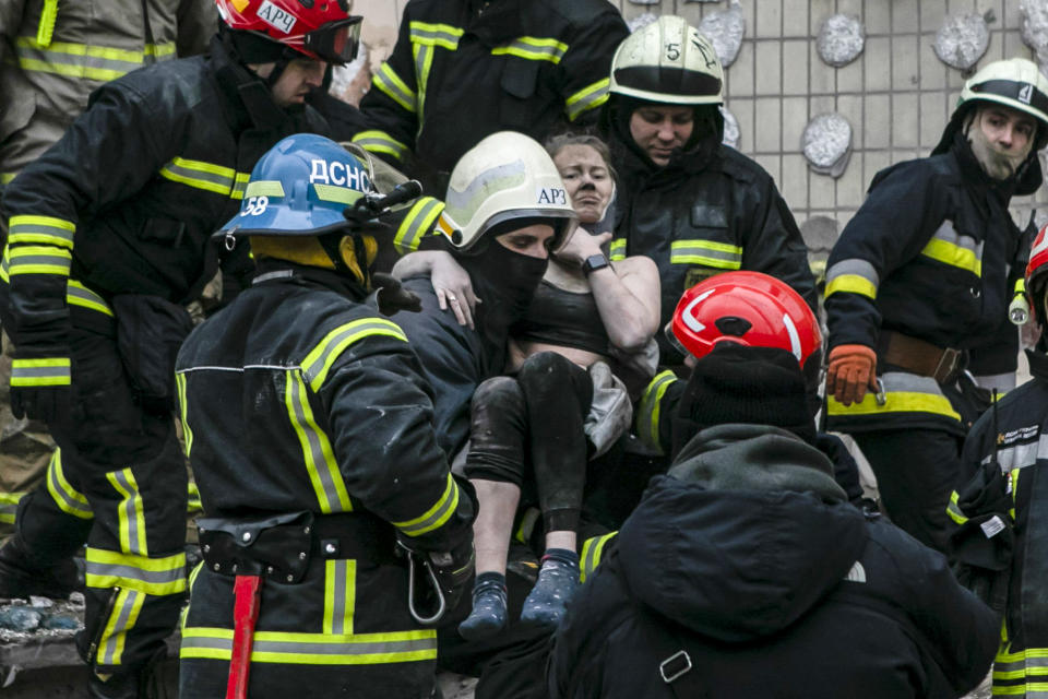 Emergency workers carry a wounded woman after a Russian rocket hit a multistory building on Saturday in Dnipro, Ukraine, on Jan. 15, 2023. (Yevhenii Zavhorodnii / AP)