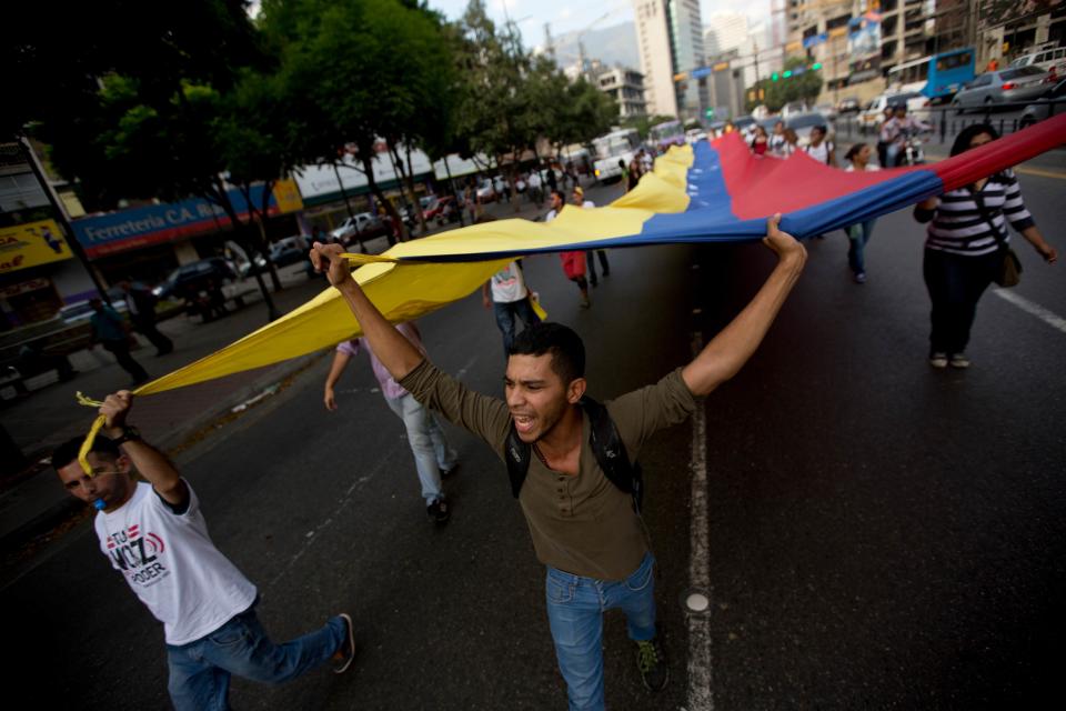 Estudiantes gritan consignas contra el presidente venezolano Nicolás Maduro mientras cargan una bandera venezolana en Caracas el viernes 25 abril de 2014. (Foto AP/Fernando Llano)