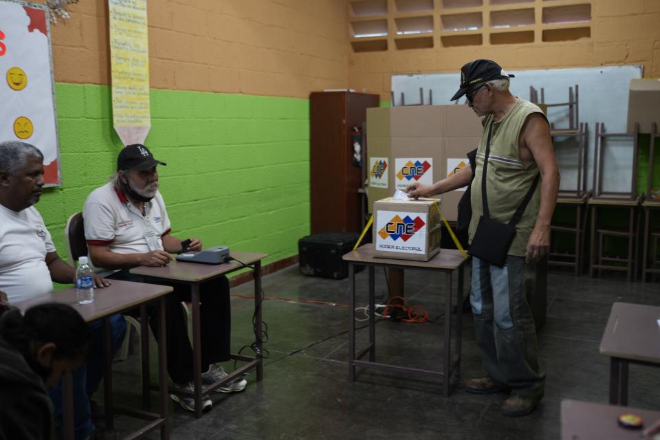 A man places his electronic voting receipt into a ballot box during a referendum about the future of a disputed territory with Guyana, at a polling station in Caracas, Venezuela, Sunday, Dec. 3, 2023. (AP Photo/Ariana Cubillos)