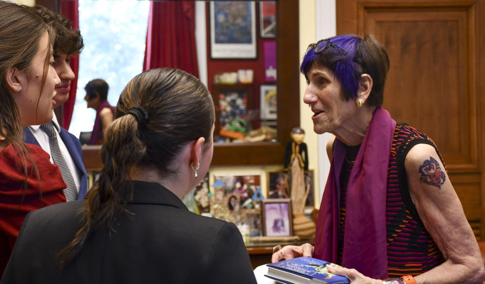 This photo provided by the Office of Congresswoman Rosa DeLauro shows Connecticut U.S. Rep. Rosa DeLauro, right, donning a tattoo, as she talks with interns, Friday, July 28, 2023, in Washington. DeLauro has stood out for years with her colorful clothing and hairstyle, but it took one of her six grandchildren to finally convince the 80-year-old lawmaker to complement her fashion-forward look with a tattoo. (Daniel Robillard/Office of Congresswoman Rosa DeLauro via AP)
