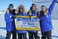 The Test Your Limits team gets a flag to mark their achievement of reaching the South Pole.