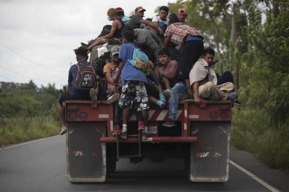 FILE - In this Oct. 2, 2020 file photo, migrants ride on the back of a freight truck that slowed down to give them an opportunity to jump on in Rio Dulce, Guatemala. Mauro Verzzeletti, director of the Casa del Migrante in Guatemala City, said the storms Eta and Iota will increase poverty on top of the violence people already faced, forcing more to migrate. (AP Photo/Moises Castillo, File)