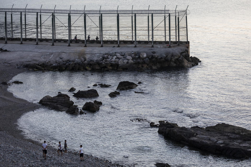 Spanish children play on the beach near the border fence separating Spain and Morocco in the district of Benzu, Spanish enclave of Ceuta, Thursday, June 3, 2021. (AP Photo/Bernat Armangue)
