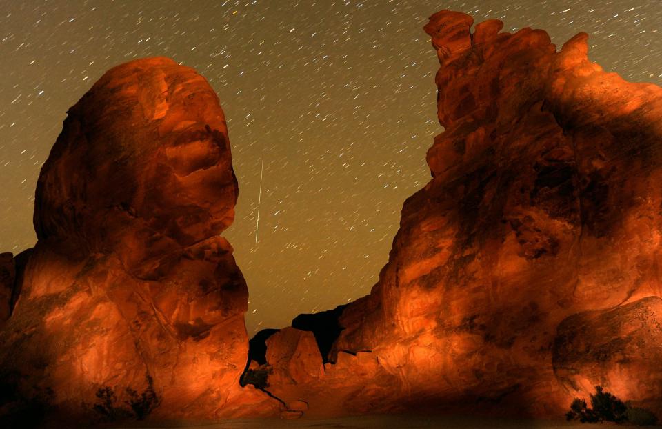 A Geminid meteor streaks between peaks of the Seven Sisters rock formation early December 14, 2010 in the Valley of Fire State Park in Nevada. The meteor display, known as the Geminid meteor shower because it appears to radiate from the constellation Gemini, is thought to be the result of debris cast off from an asteroid-like object called 3200 Phaethon. The shower is visible every December. (Photo by Ethan Miller/Getty Images) *** BESTPIX ***