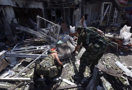 Armed pro-Russian separatists inspect wreckage near a damaged building following what locals say was a recent airstrike by Ukrainian forces in Donetsk, August 6, 2014. REUTERS/Sergei Karpukhin (UKRAINE - Tags: MILITARY CONFLICT CIVIL UNREST POLITICS) - RTR41F3Z