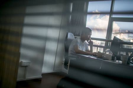 Zhang Xiongjie looks at a computer screen as he works at his office in Hangzhou, Zhejiang province, July 27, 2015. REUTERS/Chance Chan