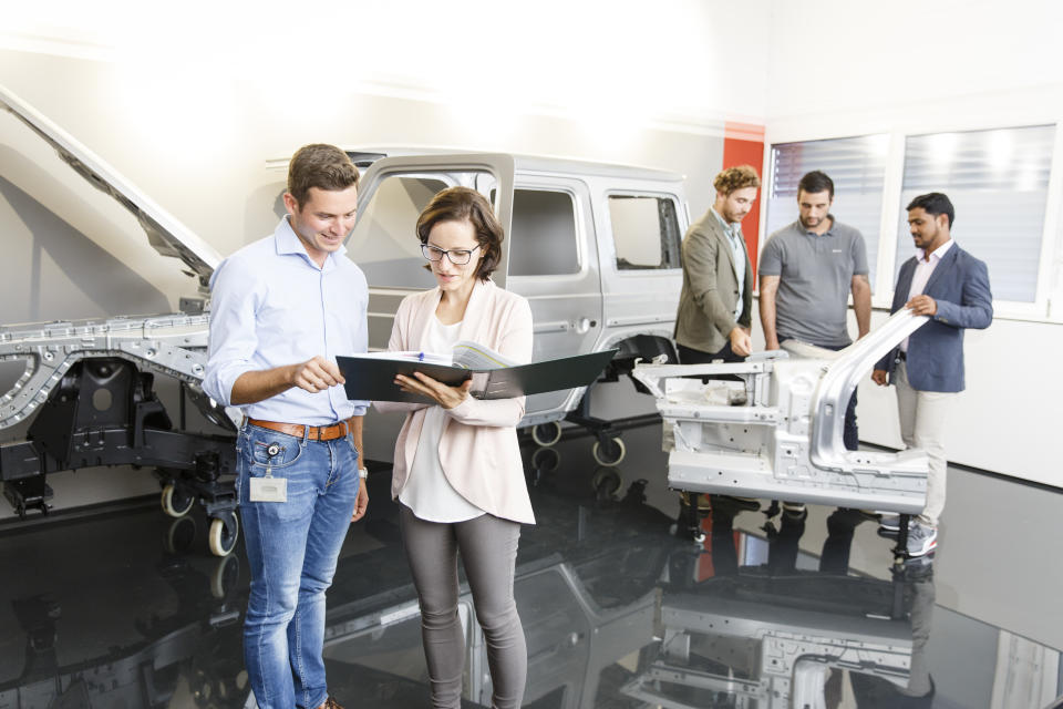 Engineers examining an auto frame.