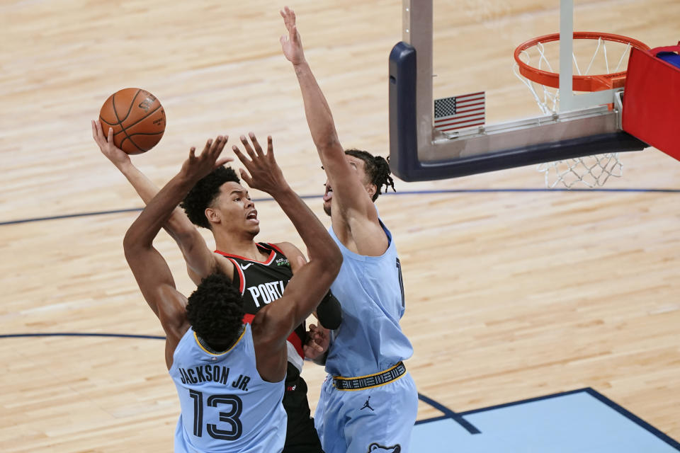 Portland Trail Blazers' Anfernee Simons, center, drives against Memphis Grizzlies' Jaren Jackson Jr. (13) and Brandon Clarke, right, in the second half of an NBA basketball game Wednesday, April 28, 2021, in Memphis, Tenn. (AP Photo/Mark Humphrey)