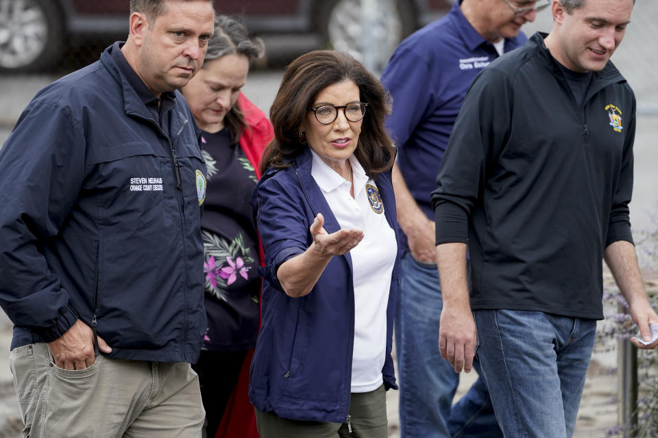 New York State Governor Kathy Hochul, center, arrives alongside Orange County Executive Steven Newhaus, left, on Main Street, Monday, July 10, 2023, in Highland Falls, N.Y. Heavy rain has washed out roads and forced evacuations in the Northeast as more downpours were forecast throughout the day. One person in New York's Hudson Valley has drowned as she was trying to leave her home. (AP Photo/John Minchillo)