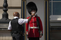 FILE - A police officer givers water to a British soldier wearing a traditional bearskin hat, on guard duty outside Buckingham Palace, during hot weather in London, July 18, 2022. Scientists said the heat wave in England and Wales on July 18 and 19 was definitely turbocharged by human-caused climate change, according to a study released Thursday, July 28, by the World Weather Attribution. (AP Photo/Matt Dunham, File)