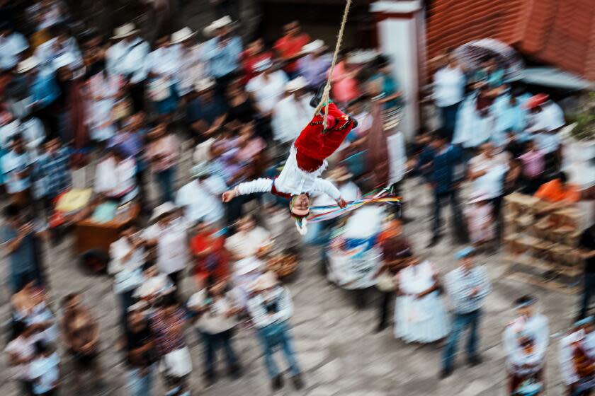 CUETZALAN, MEXICO -- OCTOBER 4, 2023: A Volador closes his eyes as he flies around the tree tied to a rope for the city's patron saint's festival in Cuetzalan, Mexico, Wednesday, Oct. 4, 2023. Across Mexico, hundreds of people in indigenous communities practice the voladores ritual, passing on the death-defying tradition from generation to generation. Today, they are working to grant the ritual legal protections, fight against the appropriation of the volador's image and find the balance between preserving the ritual's religious significance and performing it for tourists. (MARCUS YAM / LOS ANGELES TIMES)