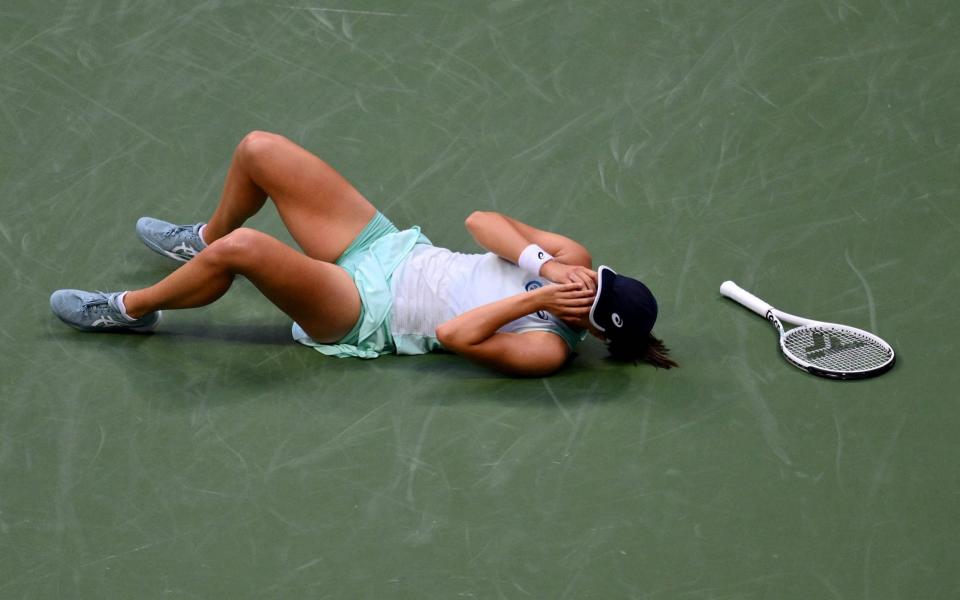 Iga Swiatek falls to the floor after beating Ons Jabeur in the US Open final - AFP