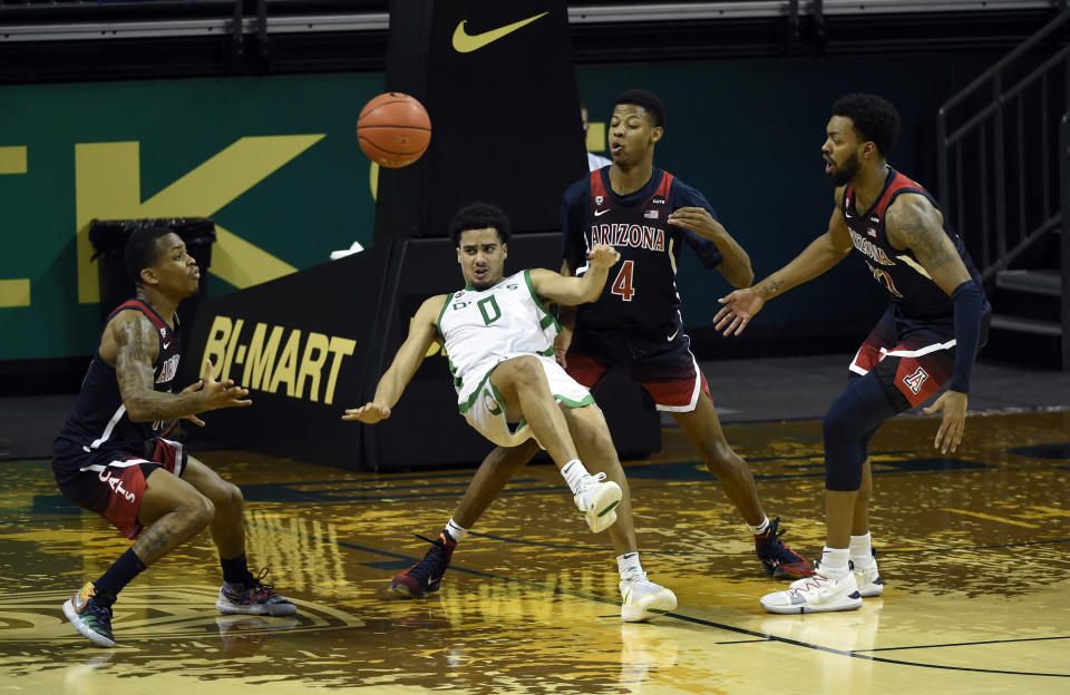 Oregon guard Will Richardson (0) falls as he passes while being defended by Arizona guard James Akinjo (13), guard Dalen Terry (4) and forward Jordan Brown (21) during the first half of an NCAA college basketball game Monday, March 1, 2021, in Eugene, Ore. (AP Photo/Andy Nelson)