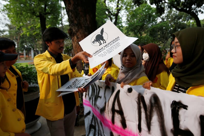 Manik Marganamahendra, a student leader at the University of Indonesia, hands out signs as he prepares to takes part in a protest over human rights, corruption and social and environmental issues in Jakarta, Indonesia