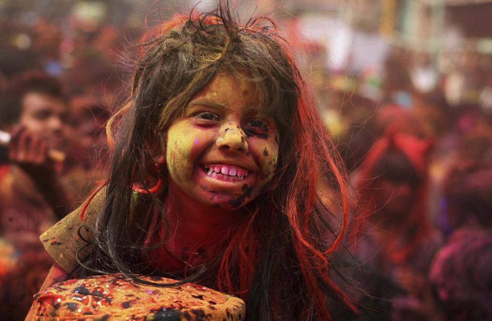 An Indian girl, face smeared with colored powder, sits on the shoulder of her father during celebrations marking Holi, the Hindu festival of colors, in Gauhati, India, Monday, March 17, 2014. The festival also marks the advent of spring. (AP Photo/Anupam Nath)