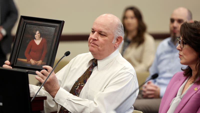 Kent Mayne holds up a photo of his daughter Mandy, who was killed by her ex-husband, as he speaks in support of SB117 during a Senate Judiciary, Law Enforcement and Criminal Justice Committee hearing in the Senate Building in Salt Lake City, on Tuesday, Jan. 24, 2023. At right is Lt. Gov. Deidre Henderson. Mandy was Henderson’s cousin.