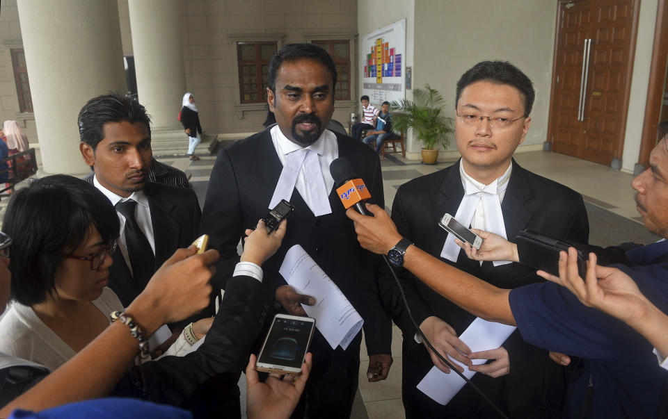 Malaysian lawyer Arunan Selvaraj, center, speaks to journalists outside a courthouse in Kuala Lumpur, Malaysia, Friday, Oct. 31, 2014. Two Malaysian teenage boys on Friday sued Malaysia Airlines and the government over the loss of their father on Flight 370, the first lawsuit filed by the family of a passenger of the jetliner that mysteriously disappeared eight months ago. (AP Photo) MALAYSIA OUT