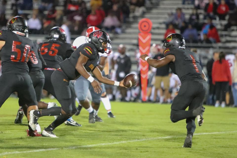 New Bern's Damaree Tucker hands the ball off to Aronne Herring on Friday night.