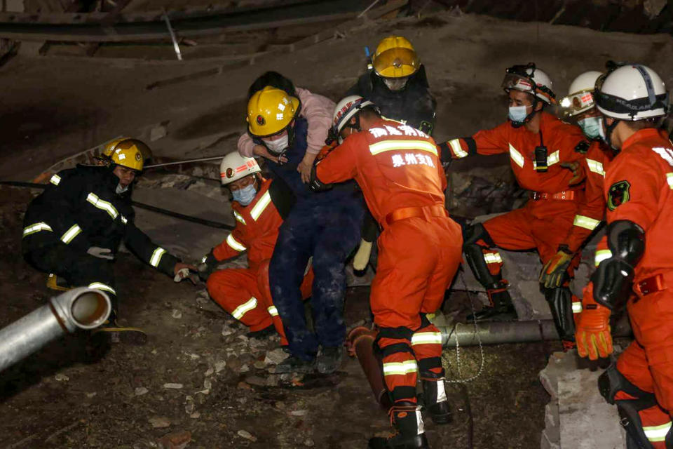 A woman (on the back) is rescued from the rubble of a collapsed hotel in Quanzhou, in China's eastern Fujian province on March 7, 2020. - Around 70 people were trapped after the Xinjia Hotel collapsed on March 7 evening, officials said. (Photo by STR / AFP) / China OUT (Photo by STR/AFP via Getty Images)