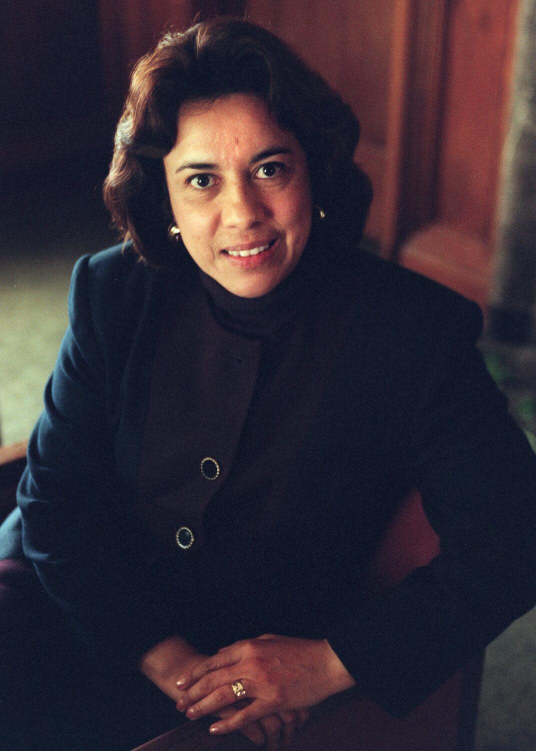 Antonia Hernández, framed waist and up, is seated with her hands folded in her lap, looking slightly up at the camera.