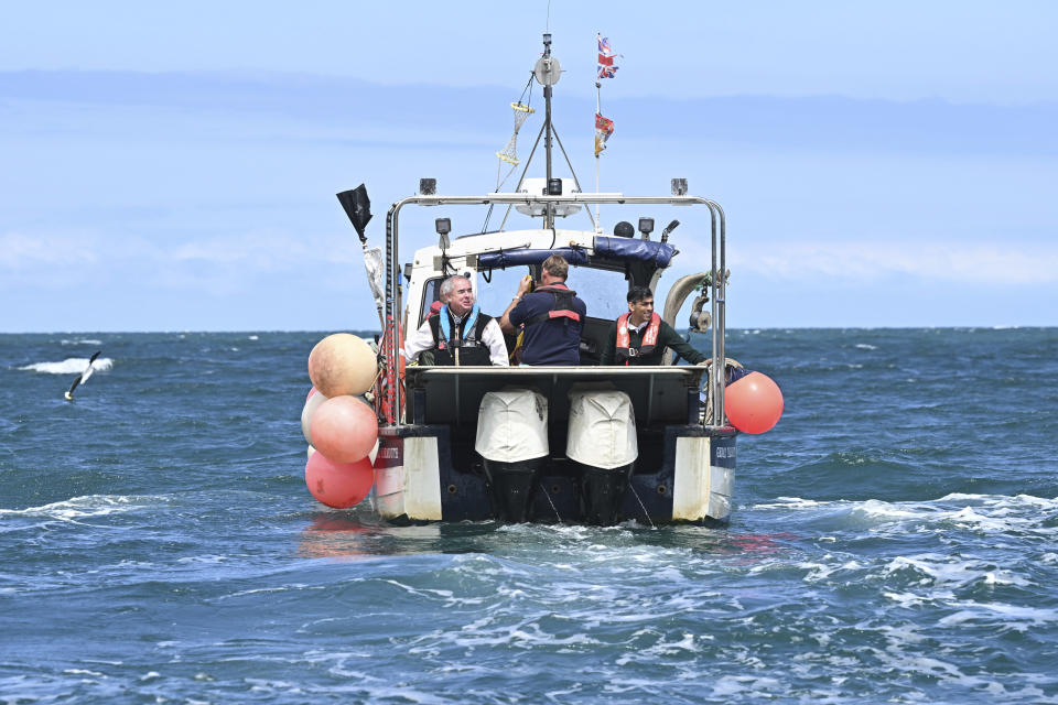 FILE - British Prime Minister Rishi Sunak, right, and West Devon MP Geoffrey Cox, left, ride on a boat in the harbour at Clovelly, England, as they collect lobster pots on Tuesday, June 18, 2024. (Leon Neal, Pool Photo via AP, File)