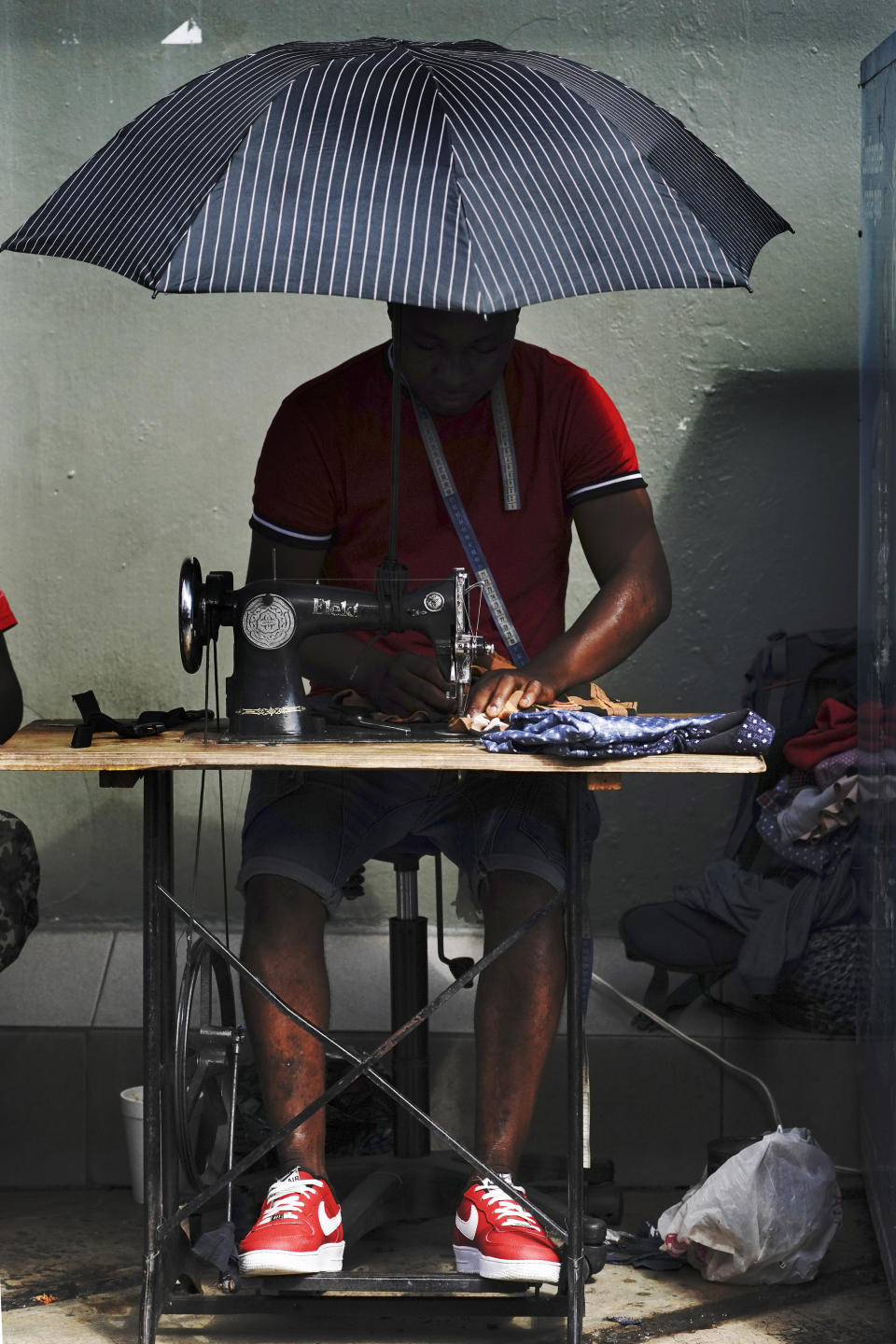 FILE - In this Sept. 3, 2021 file photo, a Haitian migrant operates a sewing machine at a market in Tapachula, Mexico. Thousands of mostly Haitian migrants have been stuck in the southern city of Tapachula, many waiting here for months and some up to a year for asylum requests to be processed. (AP Photo/Marco Ugarte, File)