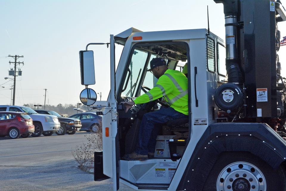 A city solid waste employee prepares to close the door and depart Monday from the city landfill in one of the new automated trash collection trucks, which has an arm to pick up the new roll carts delivered to residents in February.