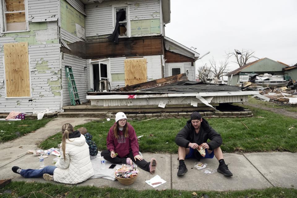 Hunter Vance (derecha) y Gabrielle Taylor comen con otras personas afuera de una casa dañada tras una fuerte tormenta, el viernes 15 de marzo de 2024, en Lakeview, Ohio. (AP Foto/Joshua A. Bickel)