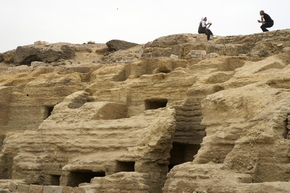 Visitors pose for pictures on top of recently unearthed ancient embalming workshops at the site of the Step Pyramid of Djoser in Saqqara, 24 kilometers (15 miles) southwest of Cairo, Egypt, Saturday, May 27, 2023. Saqqara is a part of Egypt's ancient capital of Memphis, a UNESCO World Heritage site. (AP Photo/Amr Nabil)