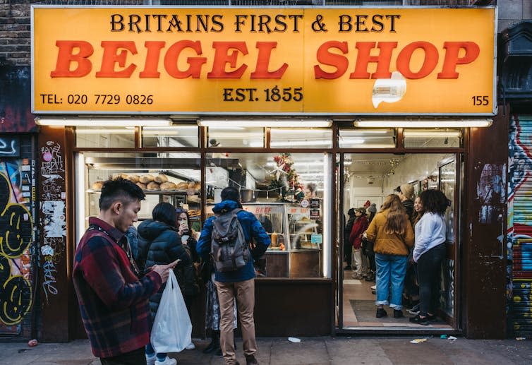 A yellow-fronted shop with people out front.