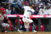 Seattle Mariners' Jonatan Clase follows through on an RBI double next to Cincinnati Reds catcher Luke Maile during the fourth inning of a baseball game Tuesday, April 16, 2024, in Seattle. (AP Photo/Lindsey Wasson)