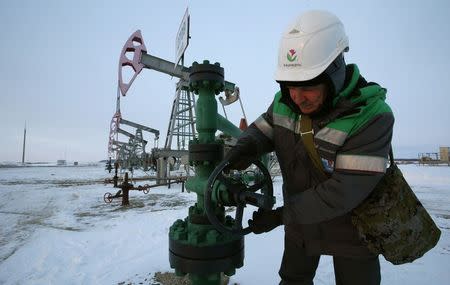 A worker checks the valve of an oil pipe at an oil field owned by Bashneft company near the village of Nikolo-Berezovka, northwest from Ufa, Bashkortostan, January 28, 2015. REUTERS/Sergei Karpukhin