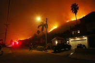 <p>A person bicycles as a section of the Thomas Fire burns on a bluff on Dec. 7, 2017 in La Conchita, Calif. (Photo: Mario Tama/Getty Images) </p>