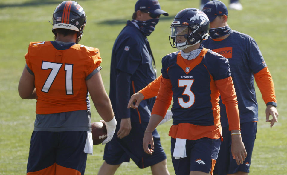 Denver Broncos quarterback Drew Lock, right, confers with guard Austin Schlottmann as they take part in drills at the team's NFL football training camp Friday, Aug. 14, 2020, in Englewood, Colo. (AP Photo/David Zalubowski)