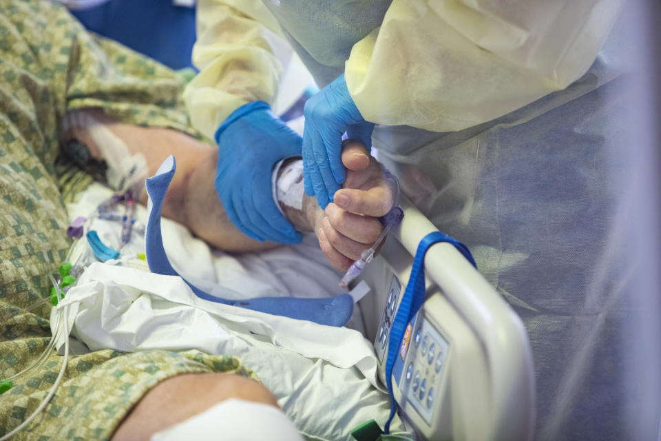 FILE - In this Aug. 31, 2021 file photo a R.N. holds the hand of a COVID-19 patient in the Medical Intensive care unit (MICU) at St. Luke's Boise Medical Center in Boise, Idaho. The Idaho Department of Health and Welfare made the announcement Thursday, Sept. 16, 2021. St. Luke's Health System, Idaho's largest hospital network, asked state health leaders to allow "crisis standards of care" on Wednesday because the increase in COVID-19 patients has exhausted the state's medical resources. (AP Photo/Kyle Gree,File)