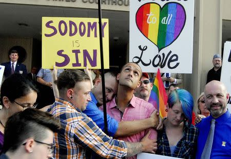 Demonstrators stand on the front steps of the federal building waving a rainbow flag in protest of Rowan County clerk Kim Davis' arrival to attend a contempt of court hearing for her refusal to issue marriage certificates to same-sex couples at the United States District Court in Ashland, Kentucky, September 3, 2015. REUTERS/Chris Tilley