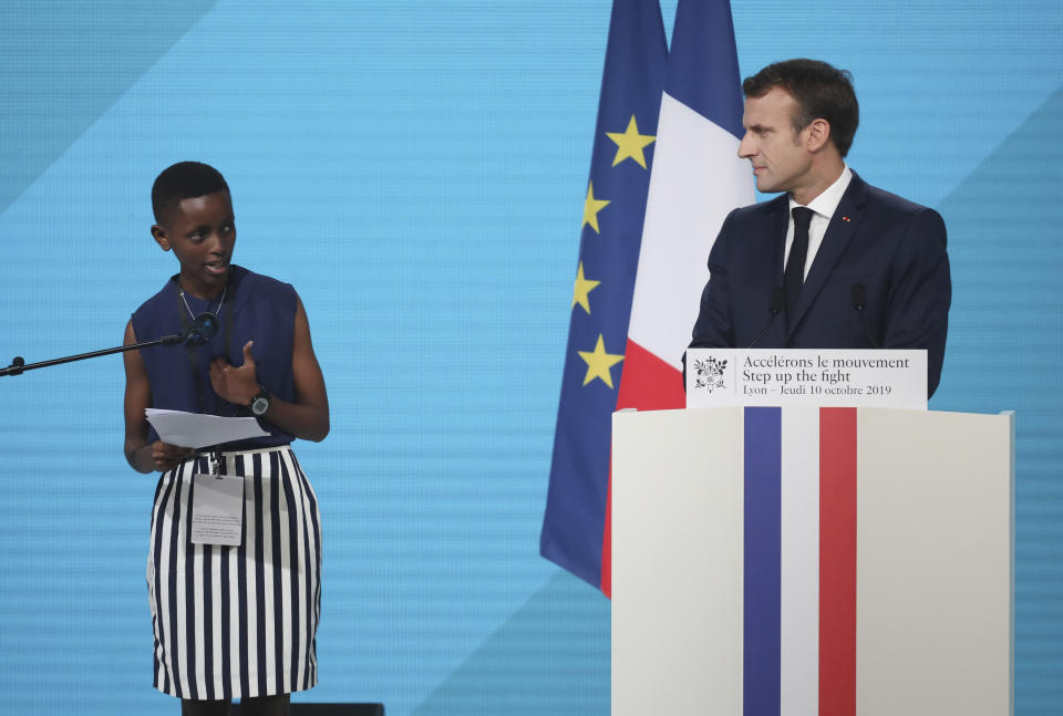 France's President Emmanuel Macron, right, listening to the goodwill ambassador of the ONG "Grandir Ensemble" Amanda Dushime at the Lyon's congress hall, central France, Thursday, Oct. 10, 2019, during the meeting of international lawmakers, health leaders and people affected by HIV, Tuberculosis and malaria. Lyon is hosting the two day Global Fund event aimed at raising money to help in the global fight against the epidemics. (AP Photo/Laurent Cipriani)