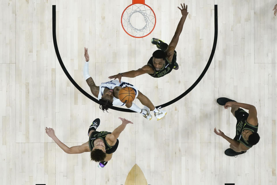 Memphis Grizzlies guard Ja Morant goes to the basket between New Orleans Pelicans forward Herbert Jones, above, and guard Dyson Daniels, below, for the game-winning shot at the buzzer in the second half of an NBA basketball game in New Orleans, Tuesday, Dec. 19, 2023. The Grizzlies won 115-113. (AP Photo/Gerald Herbert)