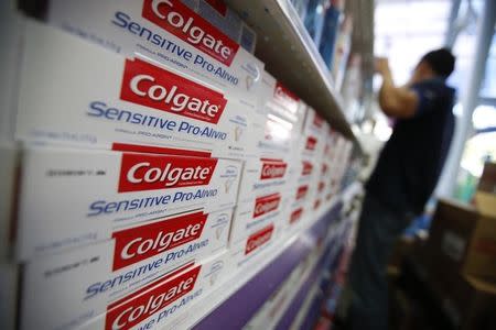 A worker arranges Colgate products on a shelf at a supermarket in Caracas February 12, 2013. REUTERS/Jorge Silva