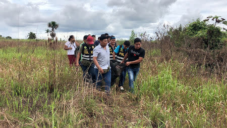 Police officers carry the body of Sebastian Woodroffe, a 41-year-old Canadian citizen, who was beaten and strangled with a rope in the jungle region of Ucayali on Friday after members of an indigenous community accused him of killing a revered medicine woman, in Pucallpa, Peru April 21, 2018. REUTERS/ Hugo Enrique Alejos