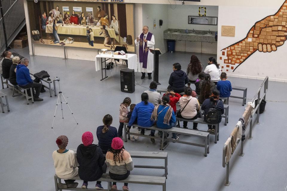 Migrants listen to Father Jose Machado, a visiting priest from Wichita, during a Mass at Kino Border Initiative on Wednesday, Dec. 21, 2022, in Nogales, Sonora, Mexico. Title 42 was scheduled to end on Dec. 21, but was granted a stay by the U.S. Supreme Court.