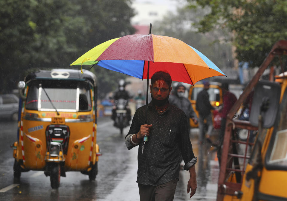 A man walks holding an umbrella in the rain in Hyderabad, India, Saturday, Nov. 20, 2021. More than a dozen people have died and dozens are reported missing in the southern Indian state of Andhra Pradesh after days of heavy rains, authorities said. (AP Photo/Mahesh Kumar A.)