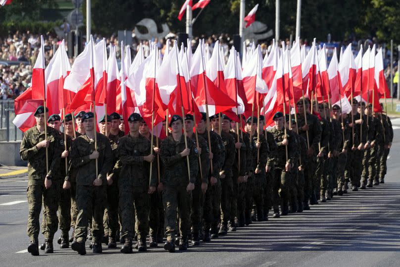 Miembros de las nuevas Tropas voluntarias de Defensa Territorial marchan con las banderas nacionales de Polonia