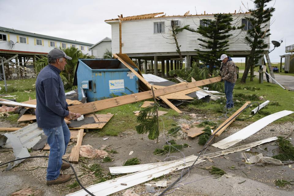 FILE - Mark Andollina, left, and Shane Holder, remove part of a roof damaged by Hurricane Zeta from the road at the Cajun Tide Beach Resort in Grand Isle, La., Oct. 30, 2020. A new study says that back-to-back hurricanes that hit the same general place in the United States seem to be happening more often. (AP Photo/Matthew Hinton, File)