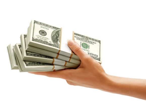 hand holding stacks of hundred dollar bills