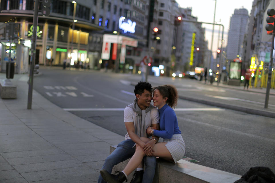 A couple laugh at the Gran Via avenue in downtown in Madrid, Spain, March 14, 2020. (AP Photo/Manu Fernandez)