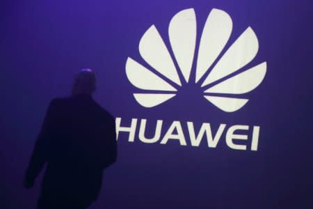 FILE PHOTO - A man walks past a logo during the presentation the Huawei's new smartphone, the Ascend P7, launched by China's Huawei Technologies in Paris, May 7, 2014.  REUTERS/Philippe Wojazer/File Photo