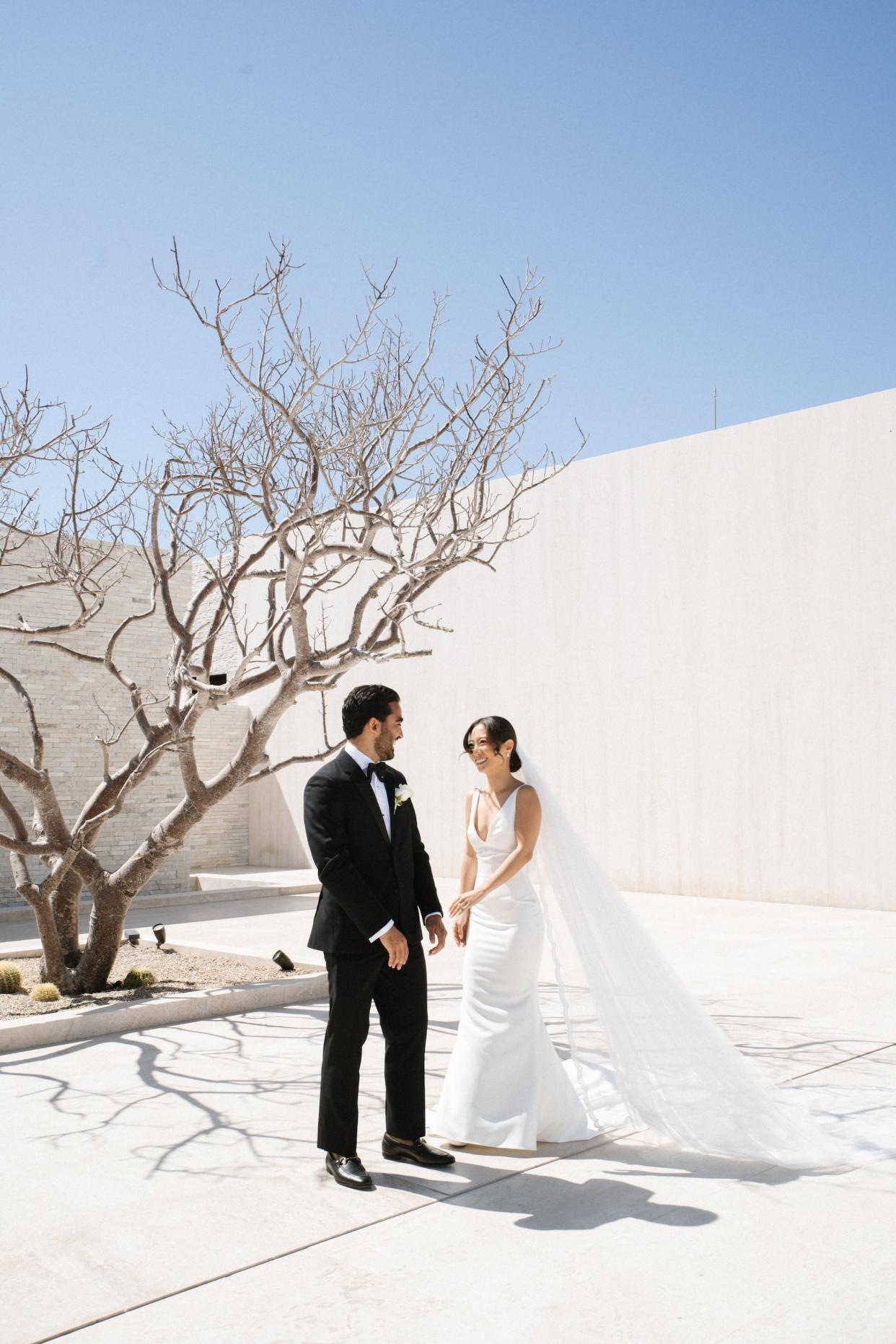 A bride gets her groom's attention on their wedding day by tapping his arm.