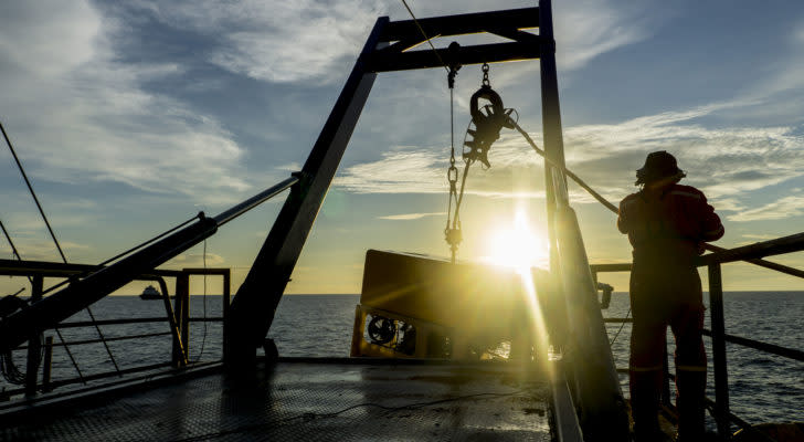 a technician lowering an exploratory robot into the ocean at dawn